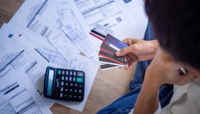stock image representing credit card debt, bills, calculator and hand full of credit cards