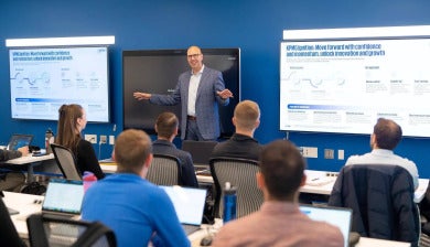 A presenter from KPMG stands next to a screen and gives a lecture to a class of DU students.