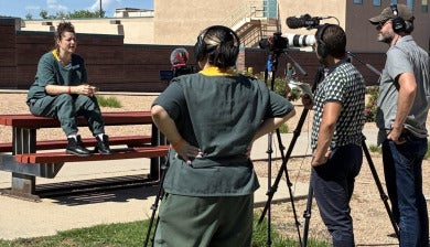 An inmate interviews another inmate behind a camera, with two producers by her side.