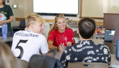 three students talking in a classroom