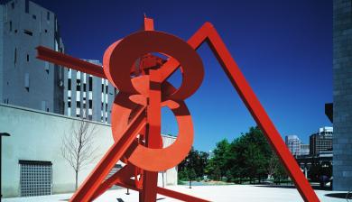 red painted steel abstract sculpture in front of a building