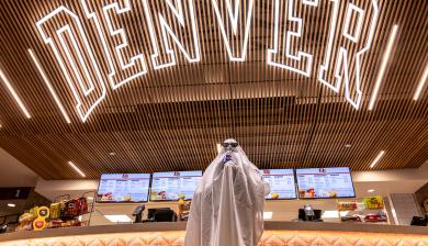 student dressed up as ghost under Denver neon sign