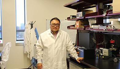 Dali Sun stands by a table in his lab