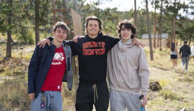 three students outside smiling at the camera