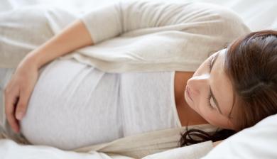 a pregnant woman sleeps on her side.
