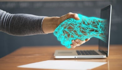 a digital hand reaches out from laptop screen to computer user