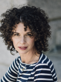 A photo of Erin Willer, a woman with dark curly hair and a blue and white striped shirt