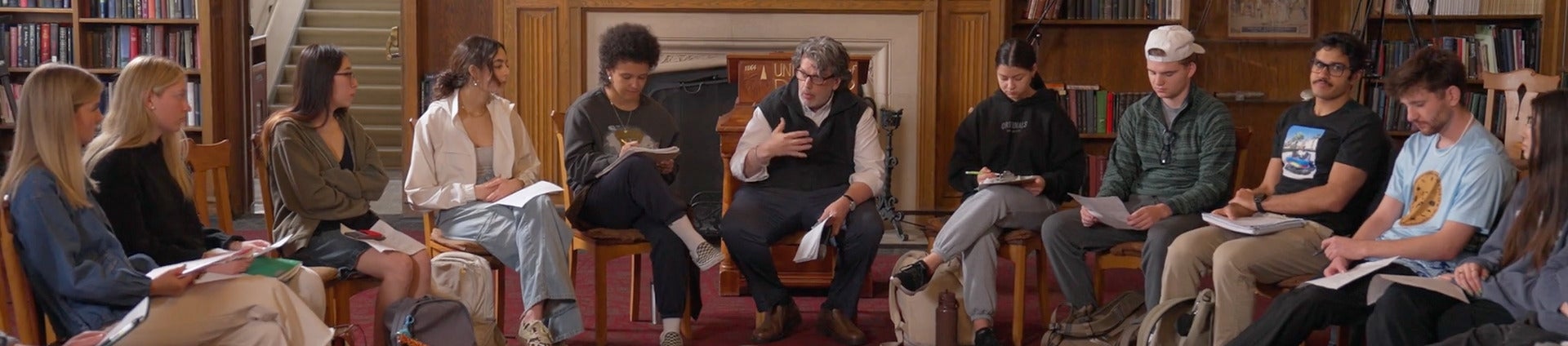 students and professor sitting in a circle and talking at debate across the curriculum