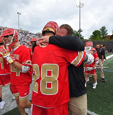 Coach Matt Brown hugs midfielder Ty Hussey.