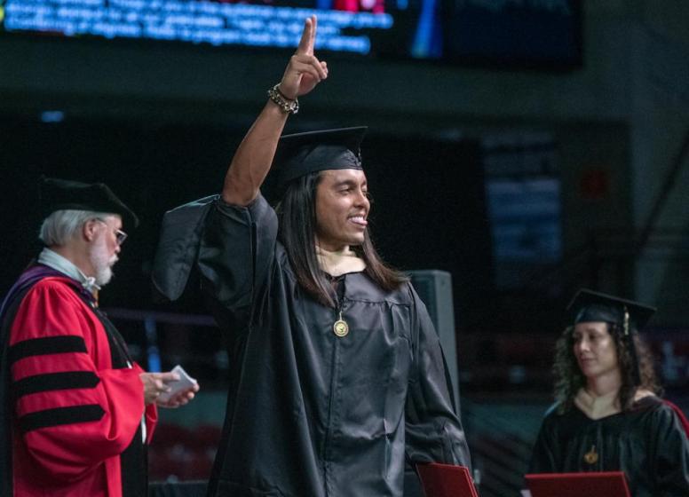 Graduate waving while walking on stage