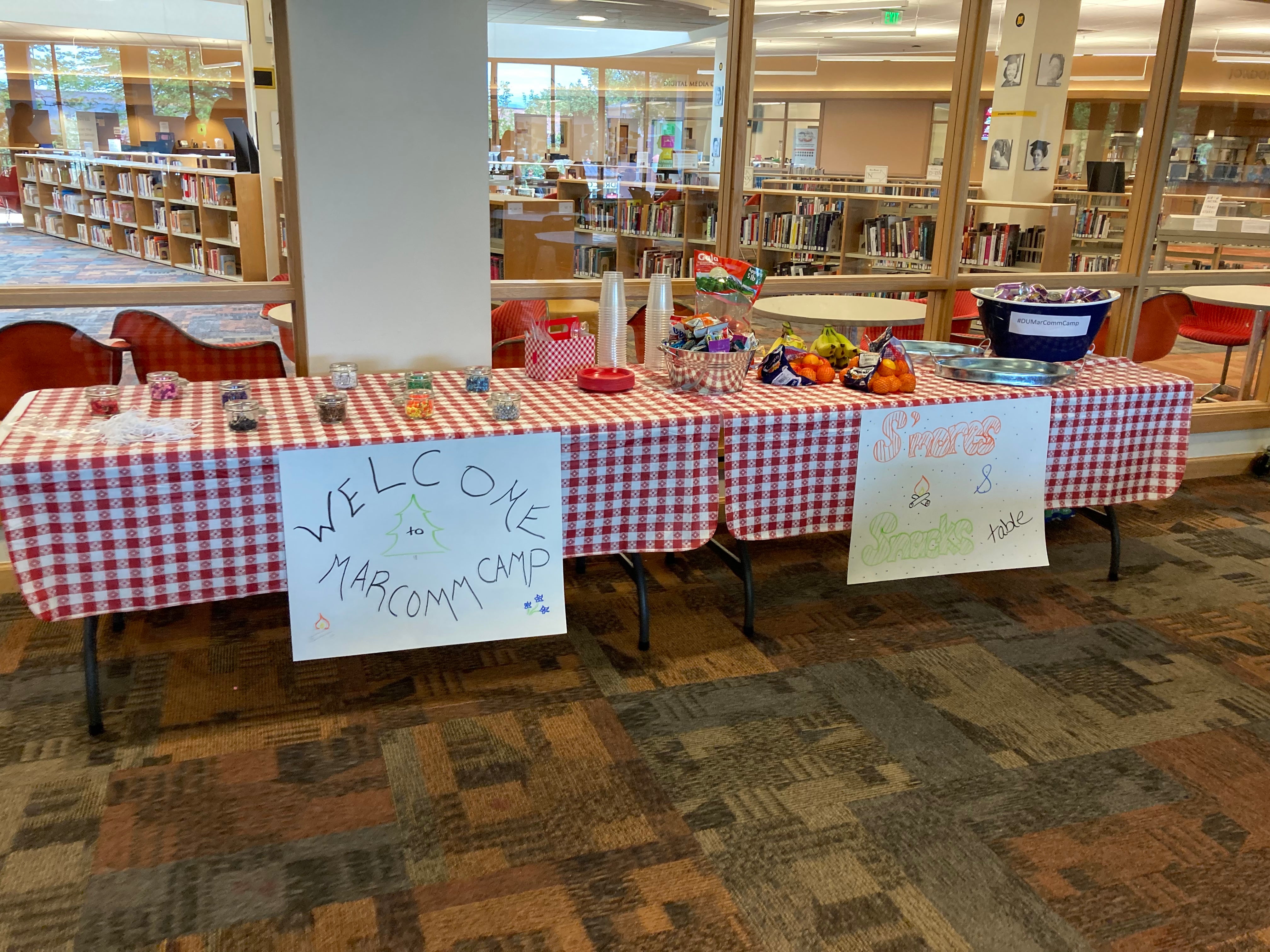 tables with supplies on them and a sign that says "welcome to marcomm camp"